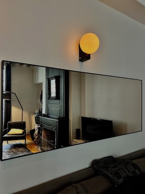 A modern living room with a large mirror, a fireplace, a sofa, and a television. -     Parisian Elegance & Modern Comfort on Île Saint-Louis (Paris)