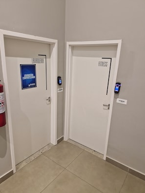 Deux portes, l’une portant l’inscription « Lavanderia Compartilhada » et l’autre « Fitness », et équipées de serrures électroniques.