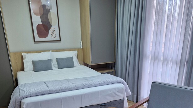 Ein Hotelzimmer mit einem Bett, einem Sessel, einem kleinen Tisch und einem Bild an der Wand.