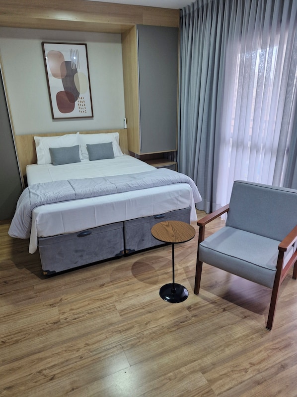 Een hotelkamer met een bed, een stoel, een tafeltje en een schilderij aan de muur.