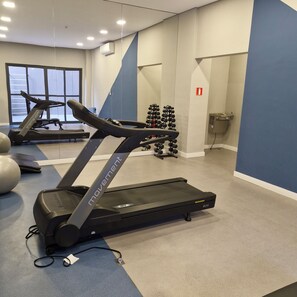 Een sportschool met loopbanden, fitnessballen en gewichten.