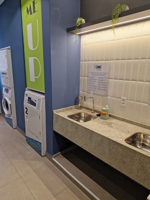A public restroom with a hand dryer, a sink, a mirror, and a sign with care instructions. - Fully equipped studio apartment with queen bed, 140m from Alto do Ipiranga metro station, with air conditioning. (São Paulo)