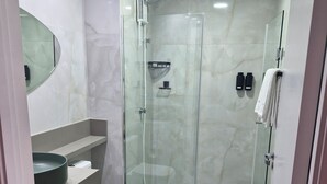 Ein modernes Badezimmer mit einer gläsernen Duschkabine, einer Toilette und einem Waschtisch mit einer Hauben-Spüle.