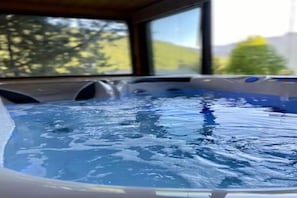 Ein Whirlpool mit Blick auf Bäume und Berge durch ein Fenster.