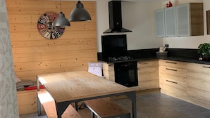 Eine moderne Küche mit Holzschränken, einem schwarzen Herd und Pendelleuchten.