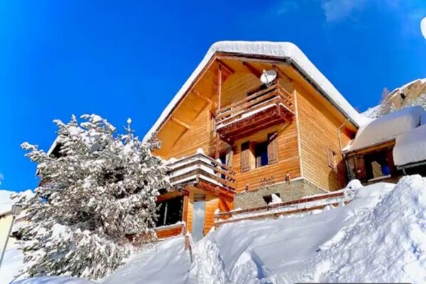 A wooden chalet with a balcony, surrounded by snow-covered trees. - Vrbo Property (Molines-en-Queyras)
