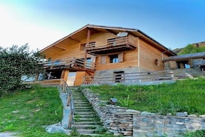 A wooden cabin with a stone staircase leading to a wooden deck. - Vrbo Property (Molines-en-Queyras)