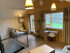 Ein gemütliches Zimmer mit Bett, Schreibtisch, Stuhl und Blick ins Freie.