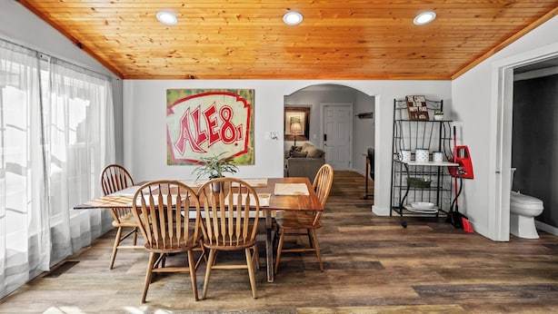 A dining area with a wooden ceiling, a table with chairs, and a large 'ALE81' sign on the wall. - South Fork River Farmhouse with River Access (Stanton)