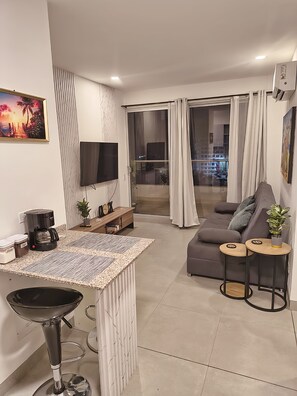 Un salon moderne avec un canapé, une table basse et un téléviseur fixé au mur.