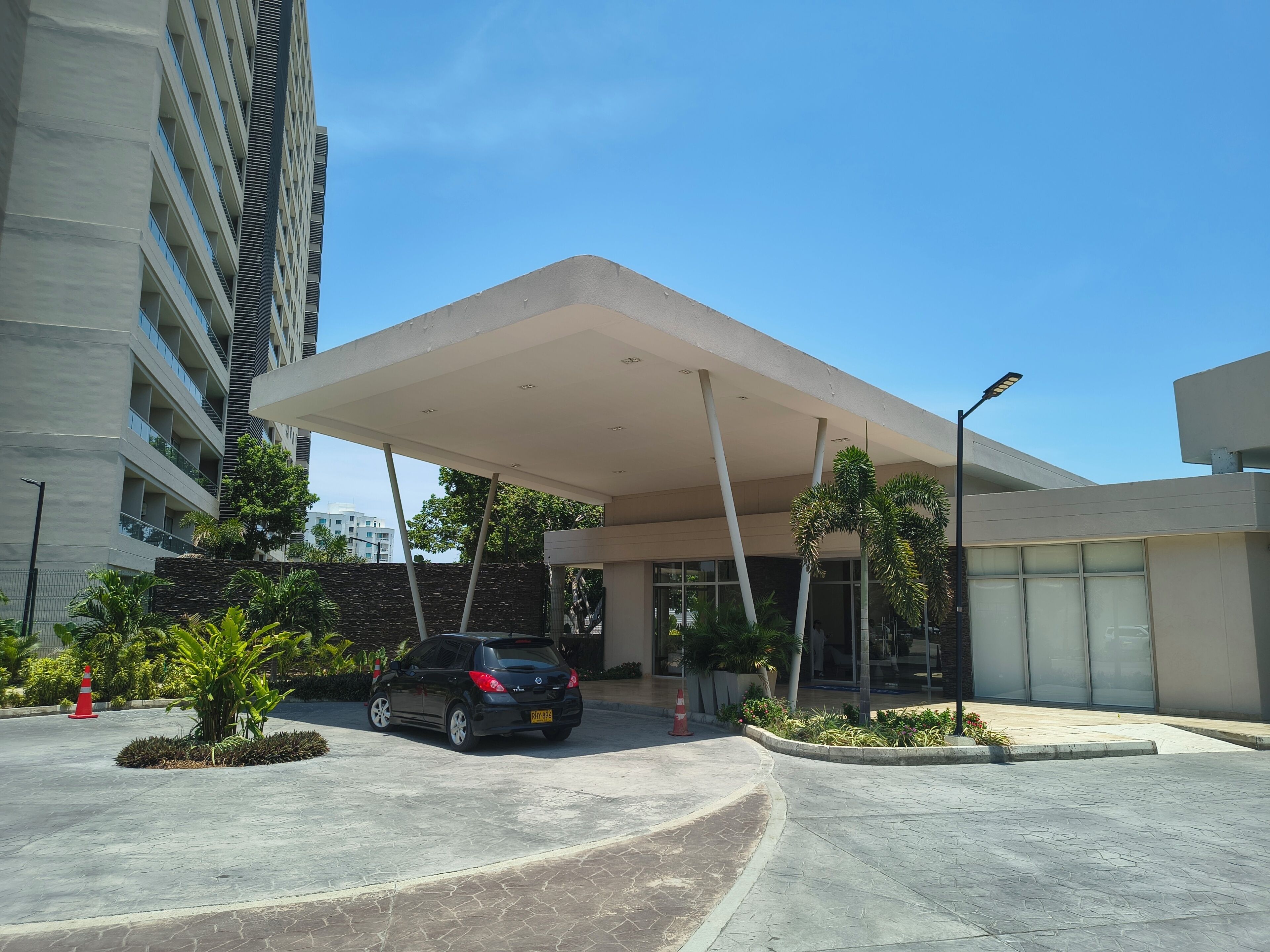 A modern building with a covered entrance, a parking area, and a street lamp.