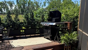 A wooden deck with a barbecue grill, outdoor furniture, and a view of a cemetery in the background. - Oxford at its Best! Location, Layout, Privacy!! (Oxford)