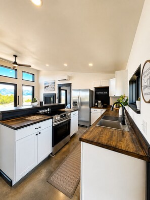 A modern kitchen with white cabinetry, stainless steel appliances, and a wooden countertop. - Modern Mountain Escape 2 Bed, 2 Bath 360 degree Sangre Views (Westcliffe)