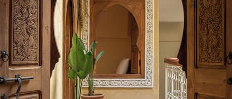 An interior hallway with wooden doors, a potted plant, and a patterned rug.