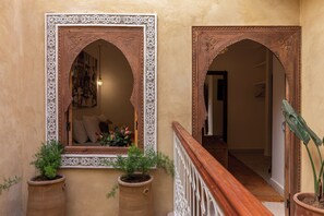 A hallway with ornate wooden doorways and a view into a room with a bed and flowers. - 4-bedroom riad in charming Marrakesh with cool AC (Marrakesh)