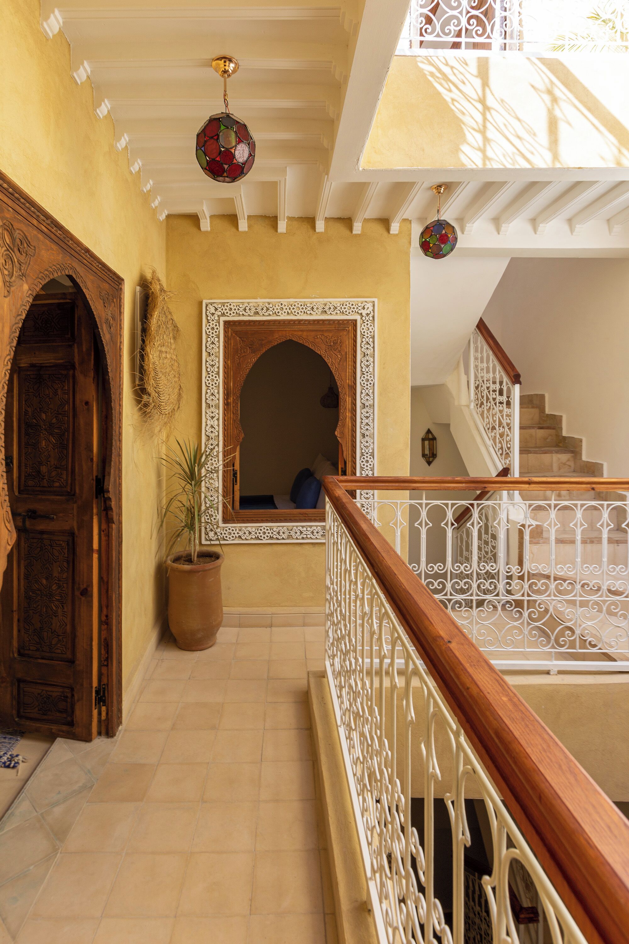 A hallway with a wooden door, a potted plant, and a staircase with a white railing.