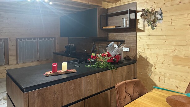 A kitchen with wooden cabinetry, a black countertop, and a dining area with a wooden table and chairs.