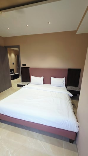 A modern hotel room with a large bed, a nightstand, and a wall-mounted TV.