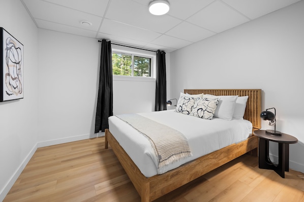 A bedroom with a wooden bed, a bedside lamp, and a window with curtains.