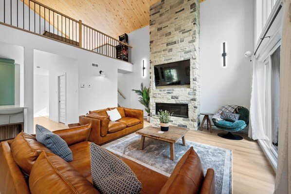 A spacious living room with a leather sofa, a coffee table, and a stone fireplace.