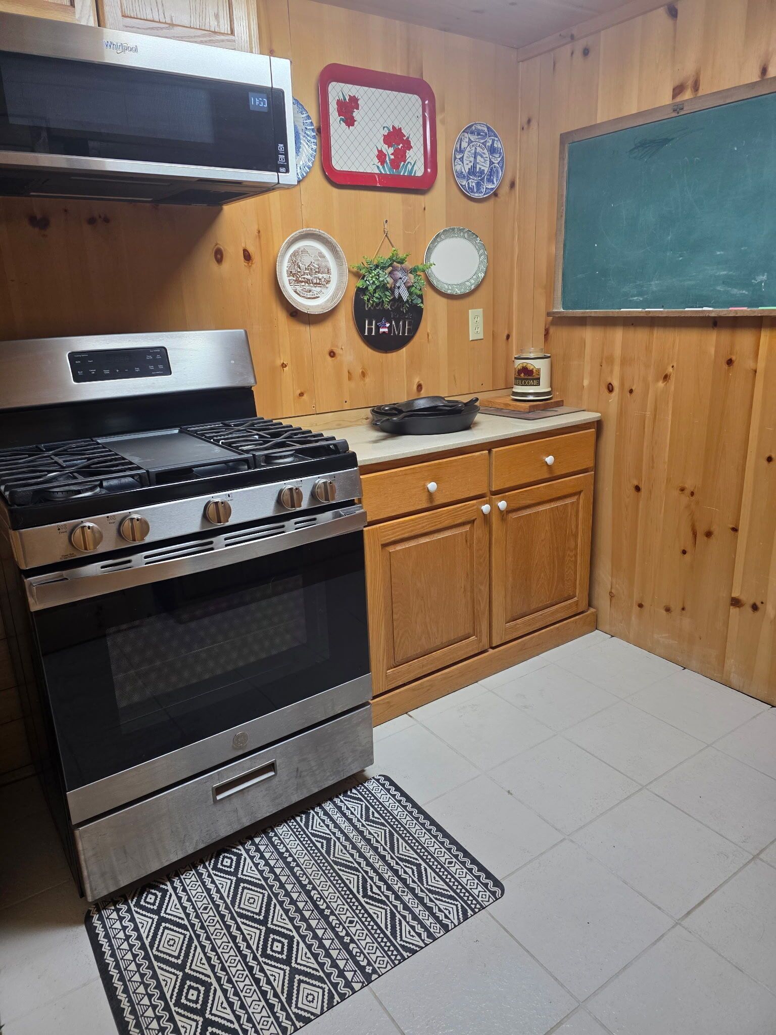 A kitchen with a stainless steel stove, wooden cabinets, and a microwave above it.
