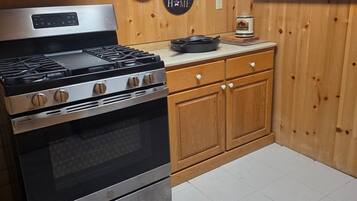 A kitchen with a stainless steel stove, wooden cabinets, and a microwave above it.