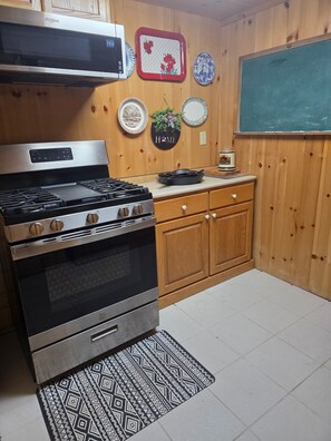 A kitchen with a stainless steel stove, wooden cabinets, and a microwave above it.