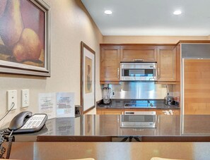 Una cocina moderna con armarios de madera, electrodomésticos de acero inoxidable y encimera de vidrio.