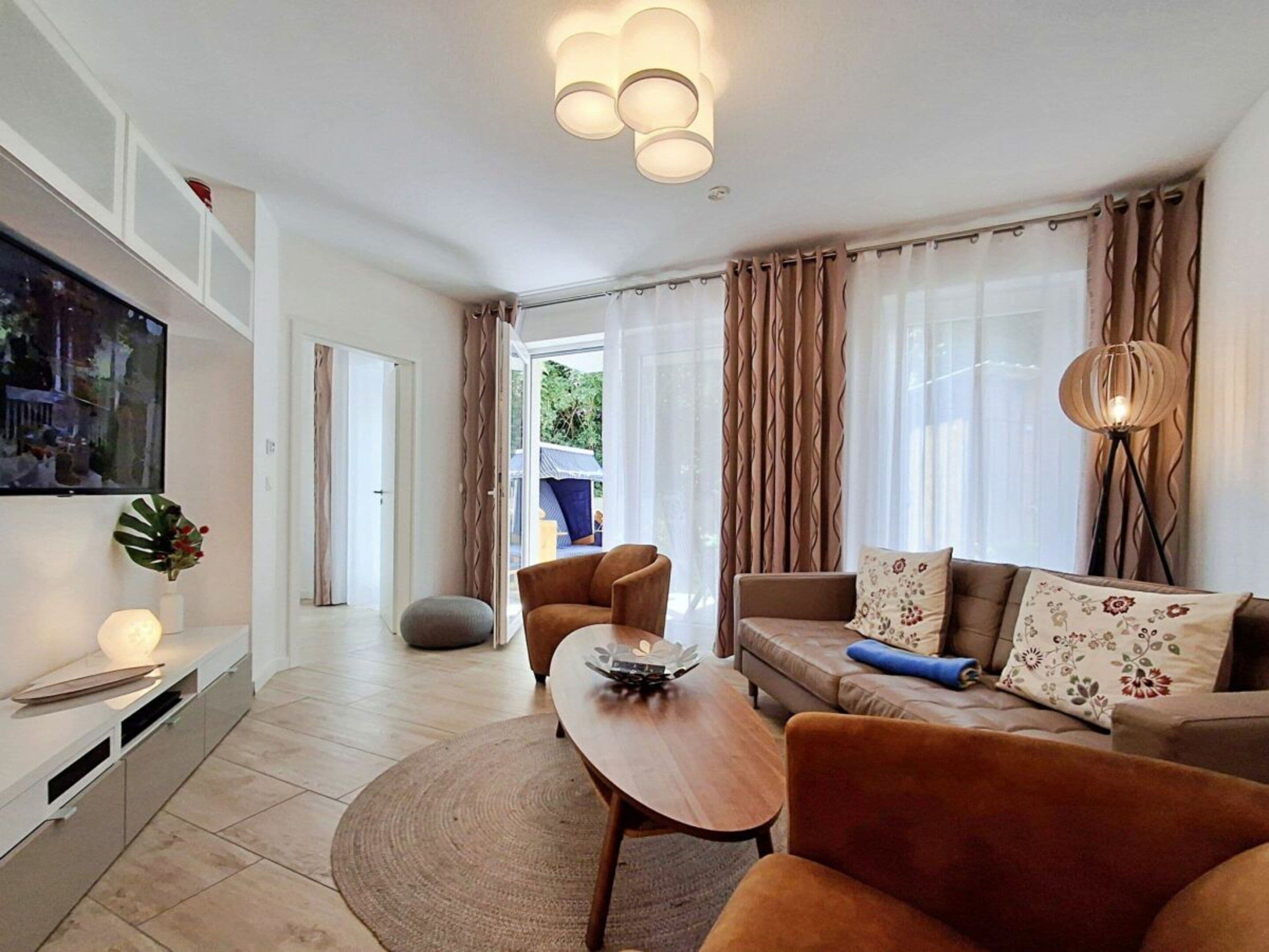 Ein modernes Wohnzimmer mit einer Couch, Sesseln, einem Couchtisch und einem Fernseher.
