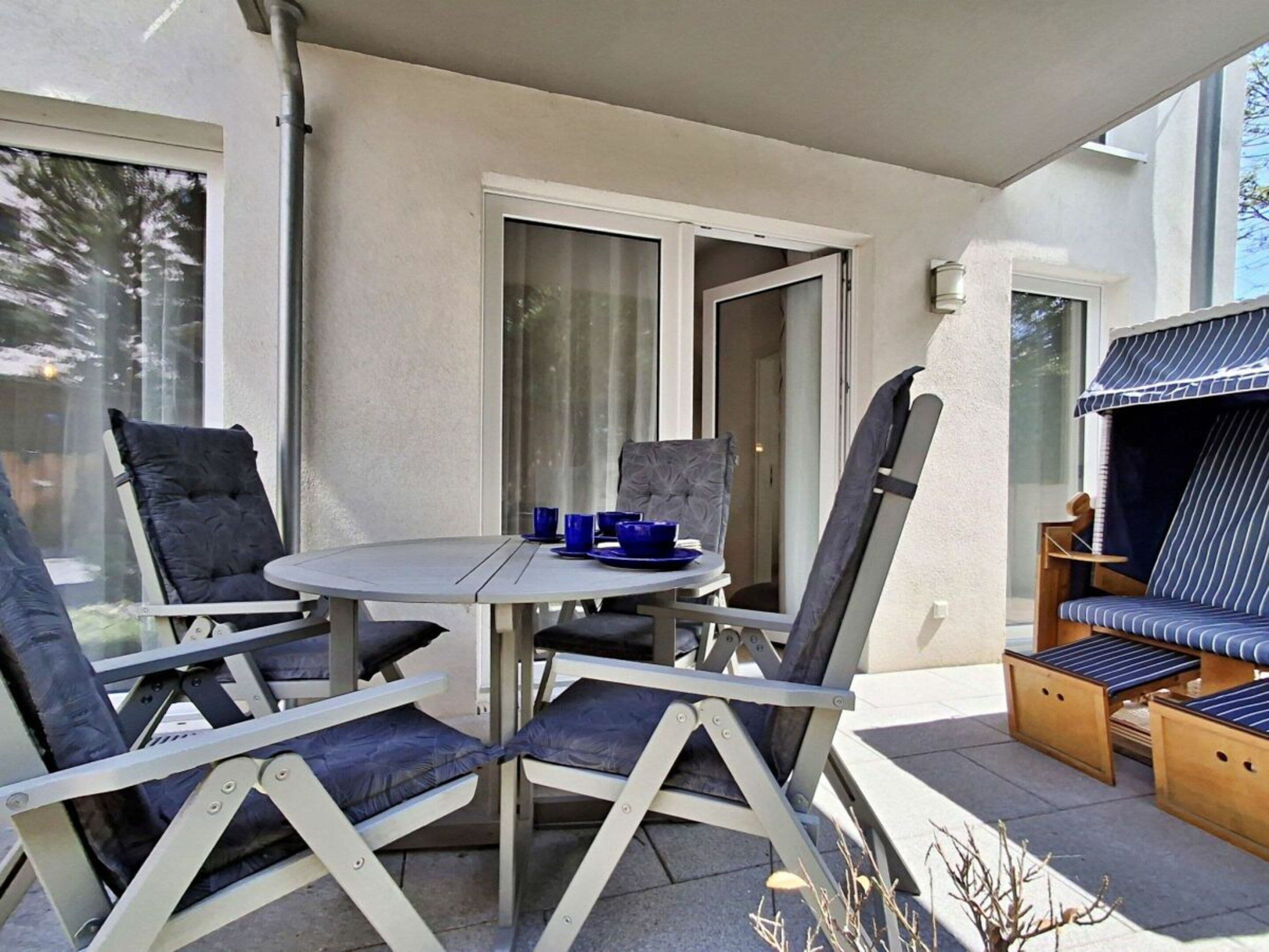 A patio with a round table and chairs, a grill, and a sliding glass door.
