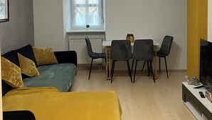 A compact living space with a bed, a small table, two chairs, and a television.