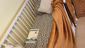 A crib with a polka-dotted mattress, a brown blanket, and a white pillow.