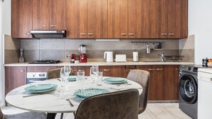 Una cocina moderna con armarios de madera, estufa integrada, cafetera y lavadora.