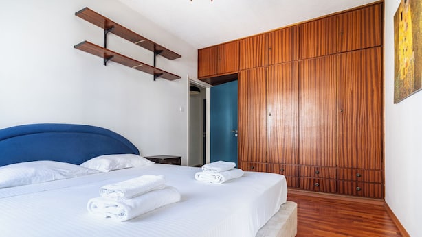 A hotel room with a bed, a wardrobe, and a painting on the wall. - Modern 2BR Apartment in Limassol (Lemesos)