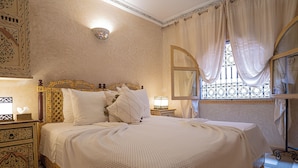 A hotel room with a large bed, ornate headboard, and a decorative wall sconce. - Authentic house in the old Medina of Marrakech. Taste the Moroccan culture (Marrakech)