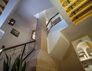 Een trap met een leuning, een wandlamp en een decoratieve spiegel.