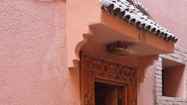 A traditional wooden door with intricate carvings, leading to a room with a tiled roof and a small window. - Authentic house in the old Medina of Marrakech. Taste the Moroccan culture (Marrakech)