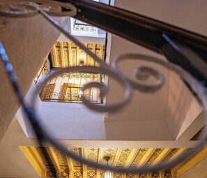 Een kamer met een kamer met een patroonplafond en een metalen spiraaltrap.