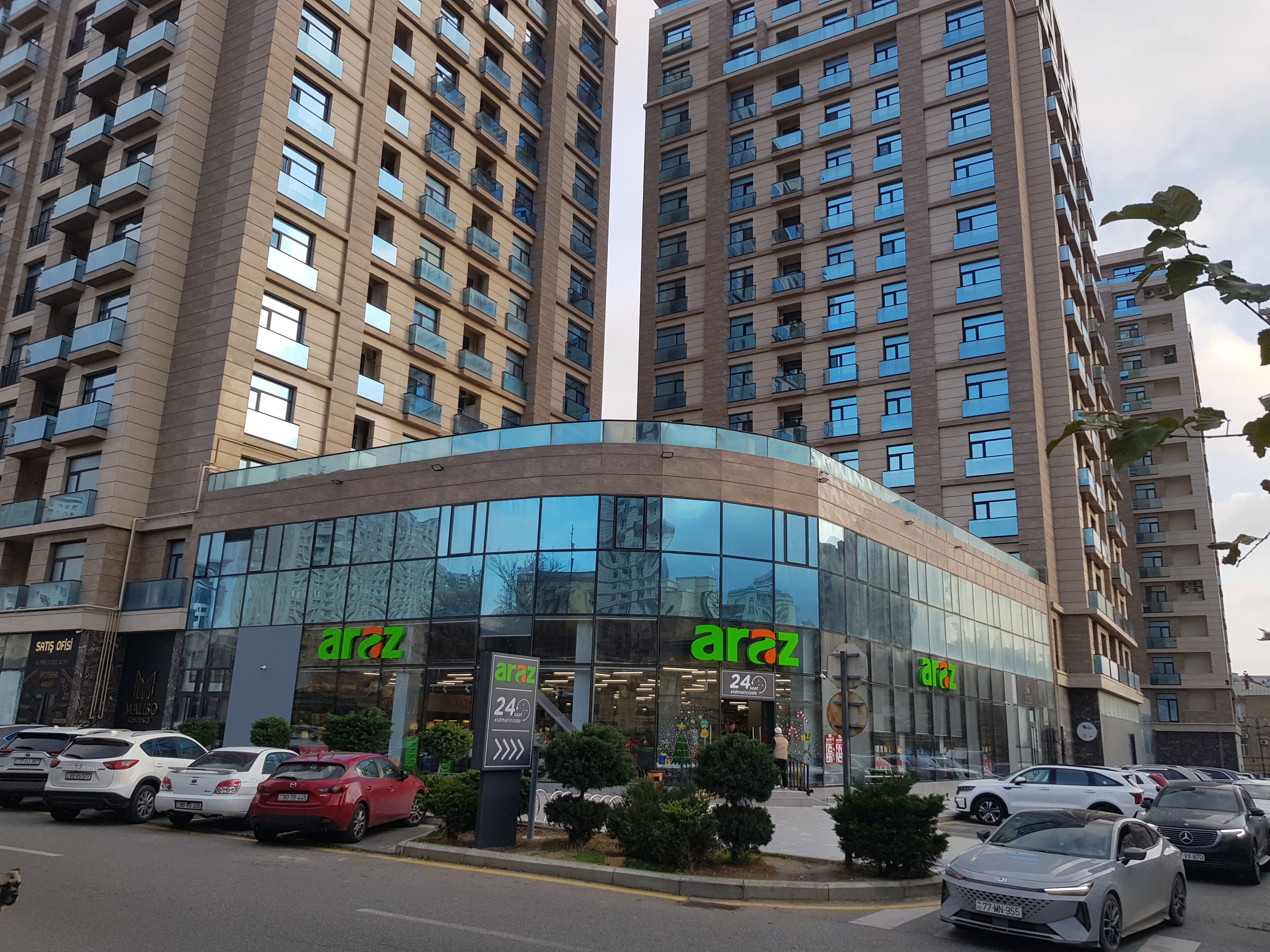 Un immeuble à plusieurs étages doté d’une façade moderne en verre et d’une devanture portant l’inscription « araz ».