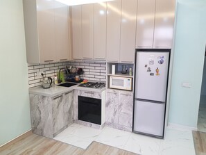 Eine kleine Küche mit integriertem Mikrowellenherd, Kühlschrank und Geschirrspüler.