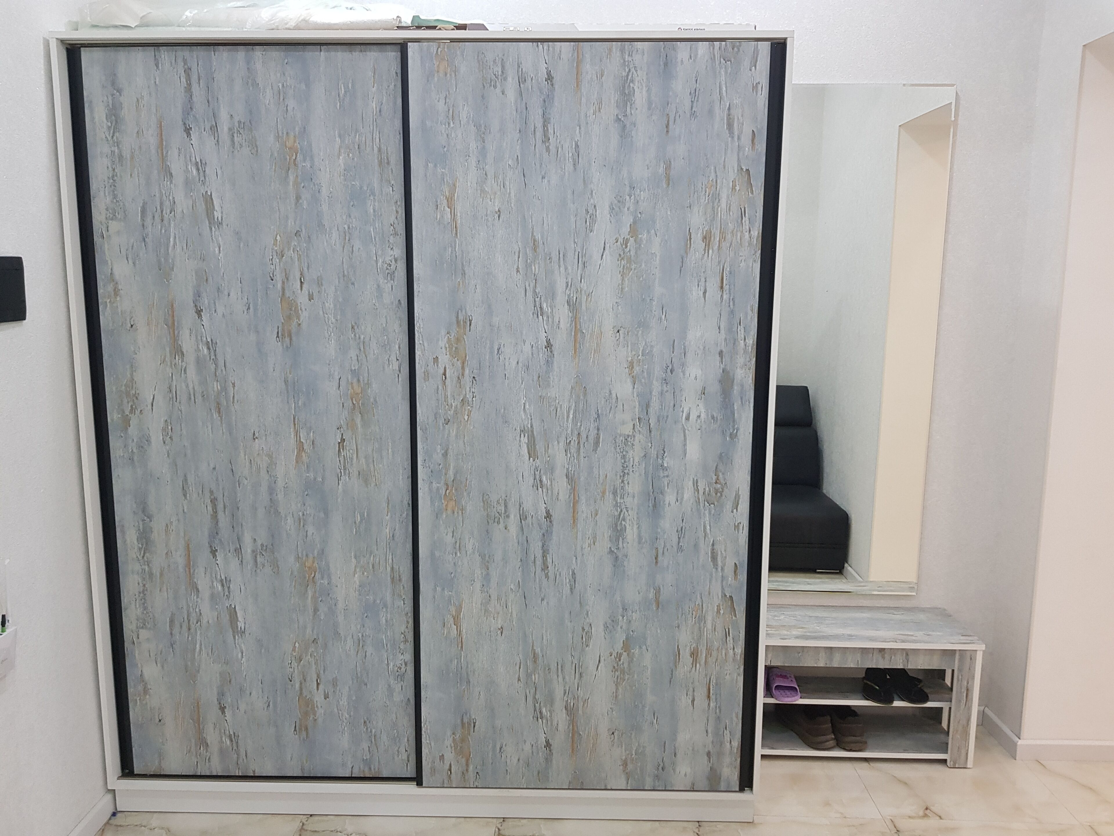 A room with a large wardrobe, a mirror, and a small table with shoes.
