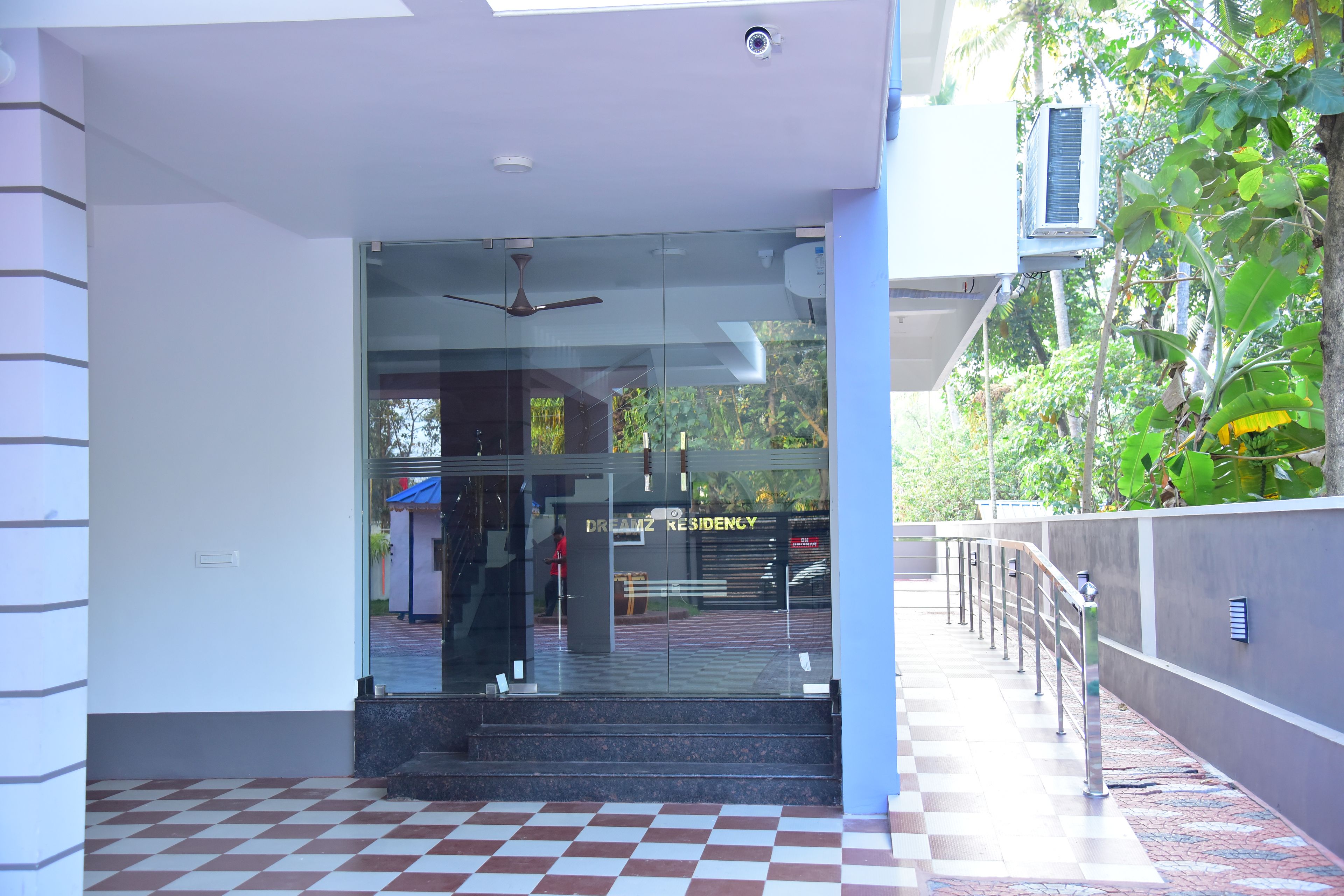 A hotel entrance with a glass door, a ceiling fan, and a checkered floor.