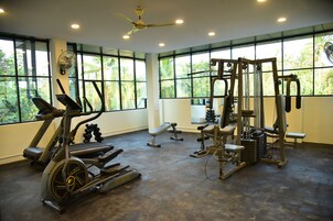 Un gimnasio con equipamiento cardiovascular, máquinas de pesas y bancos.