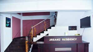 Ein Empfangsschalter mit der Aufschrift 'DREAMZ RESIDENCY' und einer Treppe im Hintergrund.