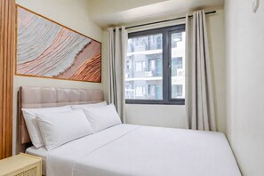 A hotel room with a bed, a window with curtains, and a wall-mounted artwork. - Shore 3 Bay City Suites 1BR Netflix + WiFi near MOA, NAIA, SMX (Pasay City)