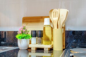 A kitchen counter with a potted plant, salt and pepper shakers, a spray bottle, and wooden utensils. - Shore 3 Bay City Suites 1BR Netflix + WiFi near MOA, NAIA, SMX (Pasay City)