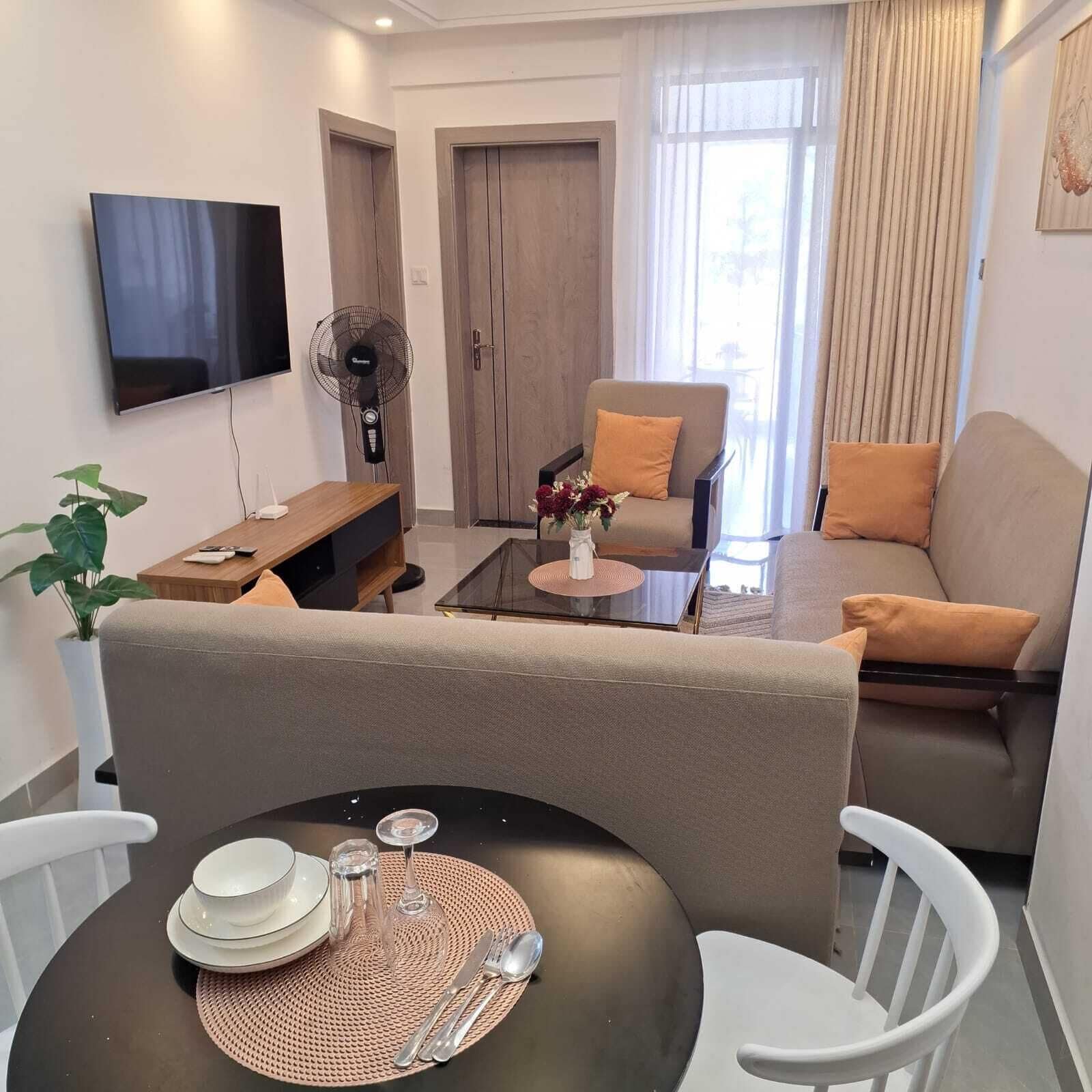 Ein modernes Wohnzimmer mit einer Couch, Sesseln, einem Couchtisch und einem Esstisch für zwei Personen.