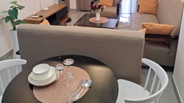 Ein modernes Wohnzimmer mit einer Couch, Sesseln, einem Couchtisch und einem Esstisch für zwei Personen.