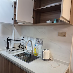 A kitchen with a sink, a black wire rack, a kettle, and a wall-mounted electrical outlet. - Beautiful 1-bedroom bed & breakfast in terrific Nairobi location (Nairobi)