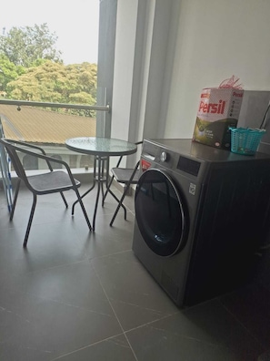 A balcony with a table and chairs, a washing machine, and a basket. - Beautiful 1-bedroom bed & breakfast in terrific Nairobi location (Nairobi)